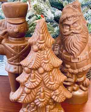 Large chocolate toy soldier and Santa figurines standing by a chocolate Christmas tree.